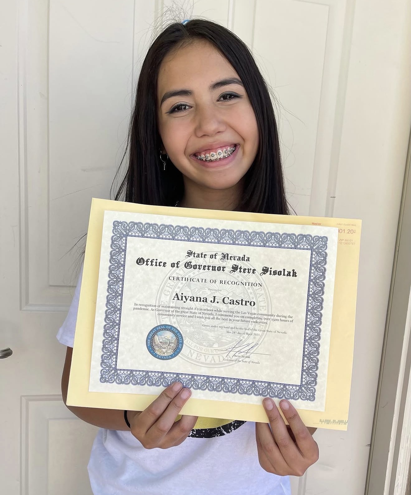 Aiyana Castro holding a certificate from Governor Steve Sisolak recognizing more than 1500 service hours